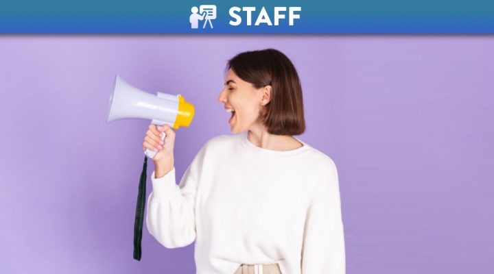 Young brunette wearing a white casual sweater shouting in a megaphone