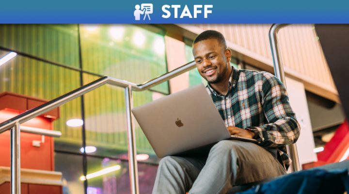 Student using a laptop on the stairs of One Elmwood
