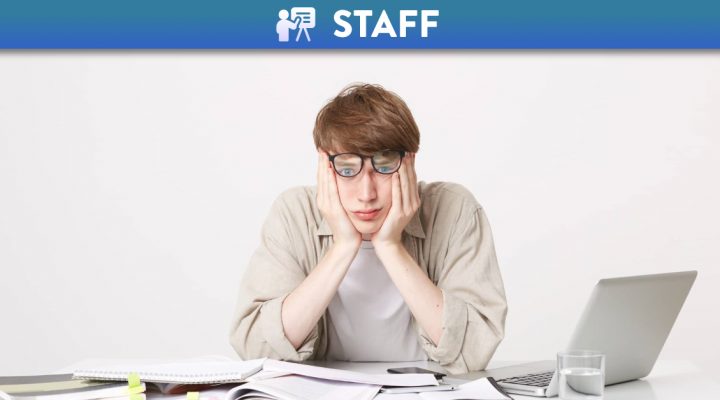 Tired student with multiple notebooks and a laptop